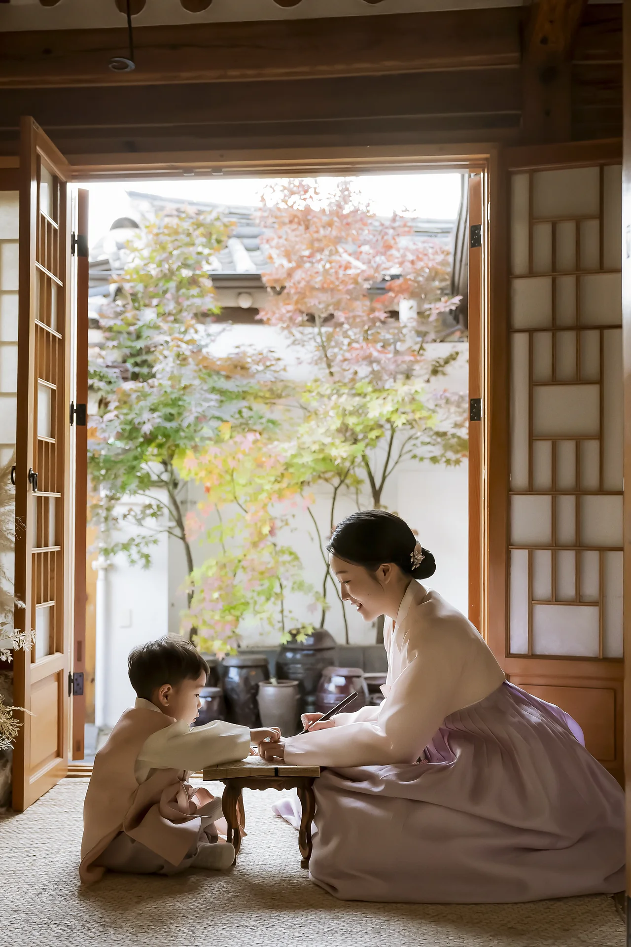 한옥 마당 가을 단풍 배경에서 엄마와 한복 아이의 다정한 돌스냅