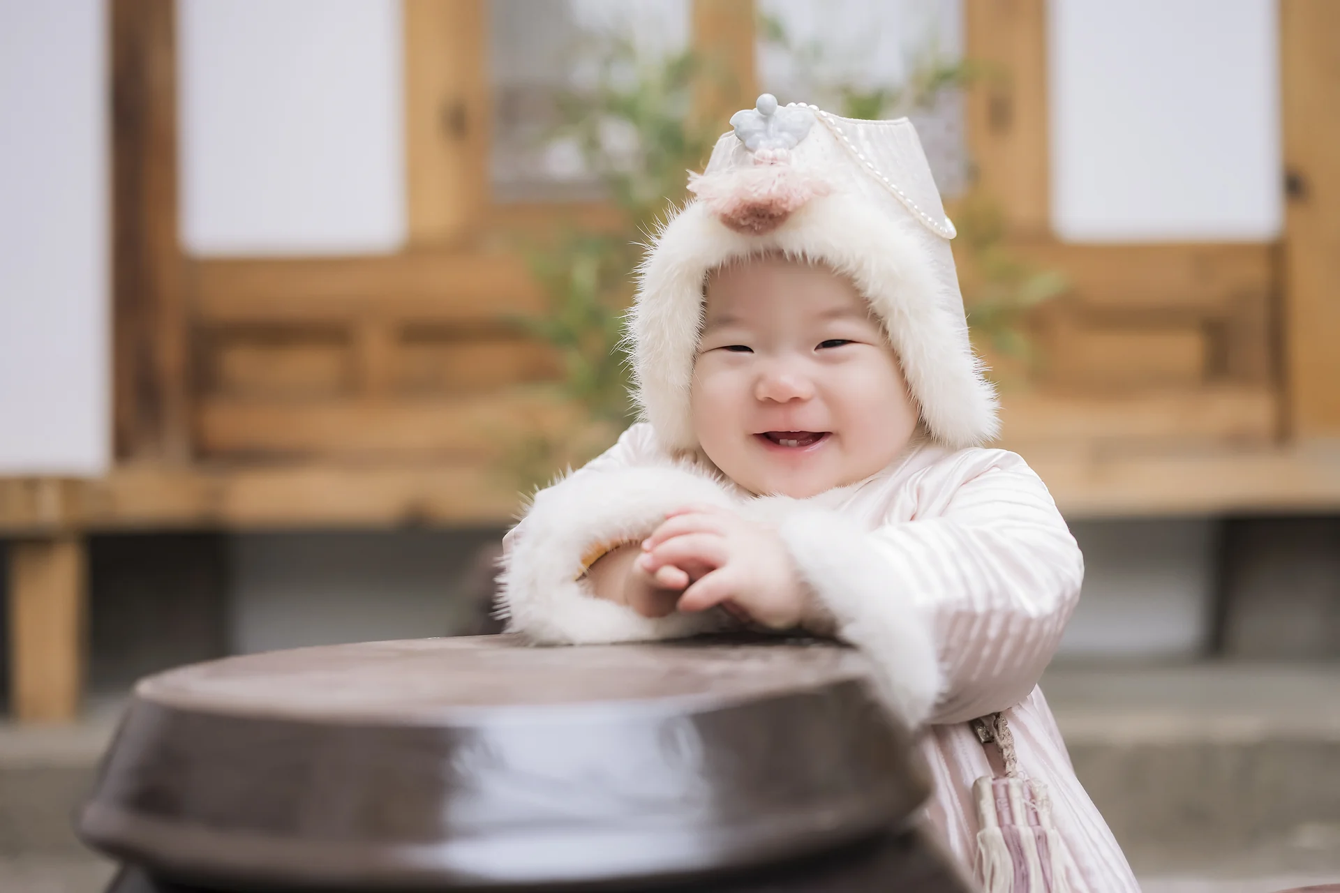 한옥 마당 장독대 앞에서 겨울 털조바위를 쓰고 웃는 돌복 아기